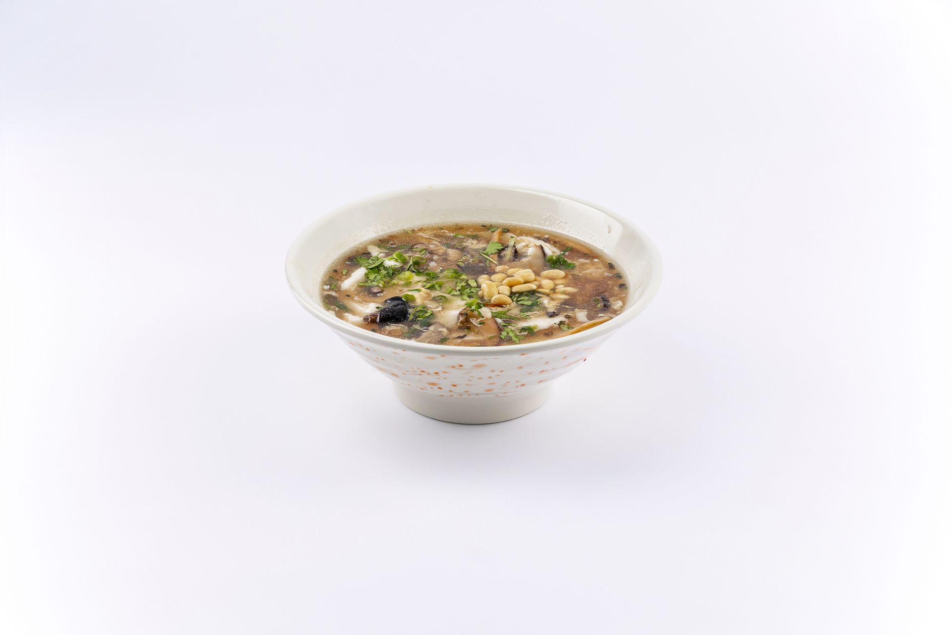 A ceramic bowl filled with a savory soup topped with fresh green onions, against a plain white background.