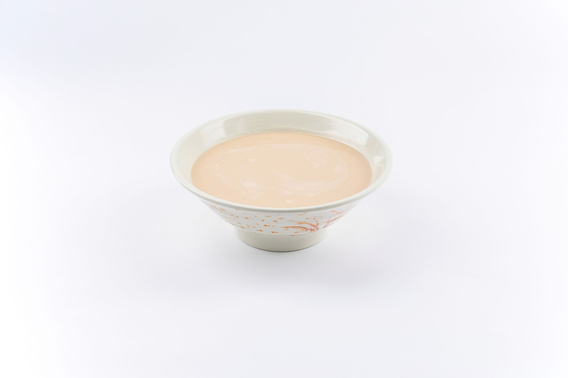 A small, light-colored bowl filled with a smooth, beige creamy soup against a plain white background.