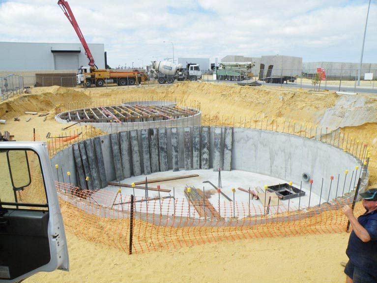 A Man Is Standing In Front Of A Construction Site With A Crane In The Background – Perth, WA - Armadale Concrete Tank Co.