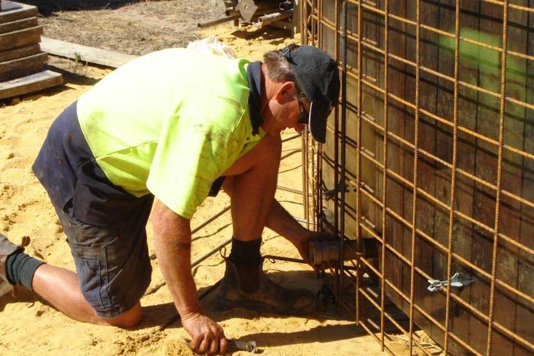 A Man In A Yellow Shirt Is Working On A Wall – Perth, WA - Armadale Concrete Tank Co.