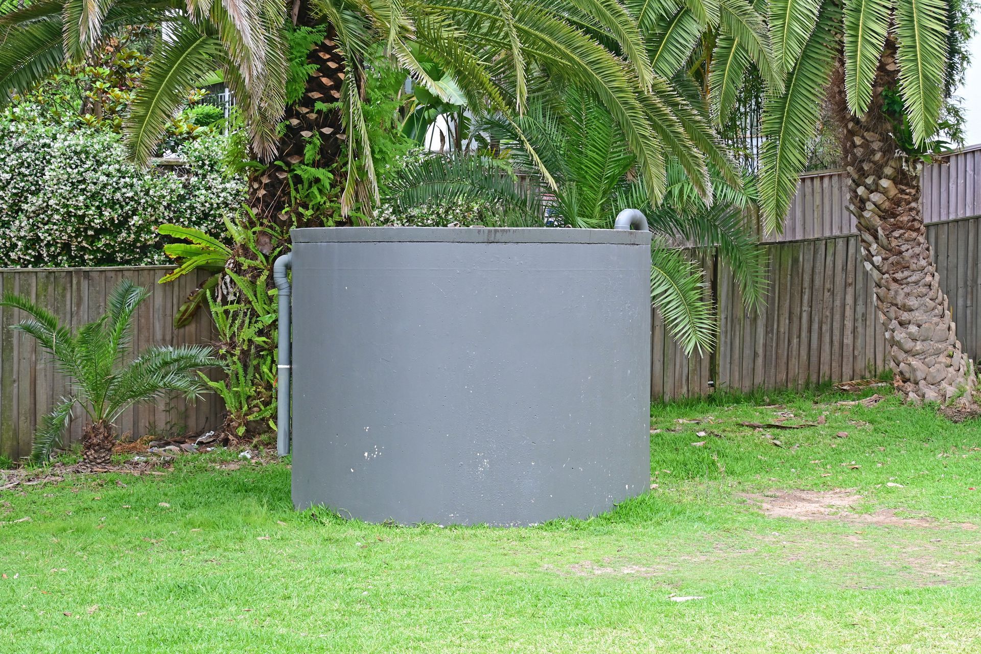 Grey concrete water tank providing durable rainwater storage in a public park.