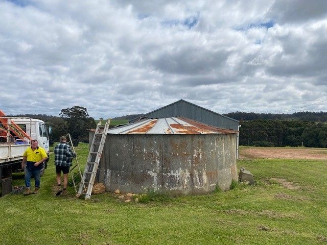 A Man Is Standing In Front Of A Large Metal Structure – Perth, WA - Armadale Concrete Tank Co.