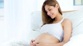 donna incinta mentre si tocca la pancia sorridendo