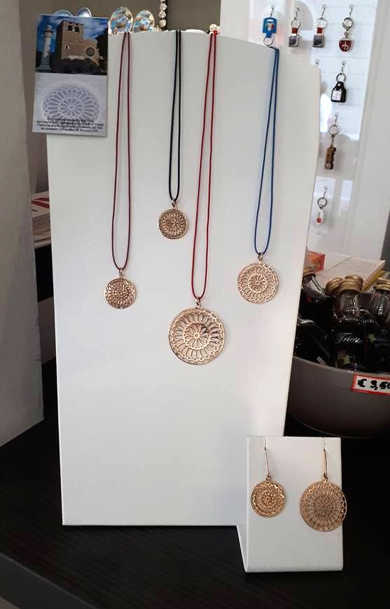 Espositore di gioielli con collane con pendenti color oro e orecchini coordinati su un supporto bianco.