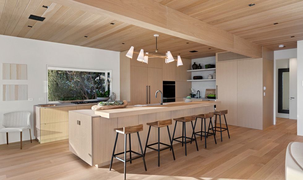 A kitchen with wooden cabinets and stools and a large island.