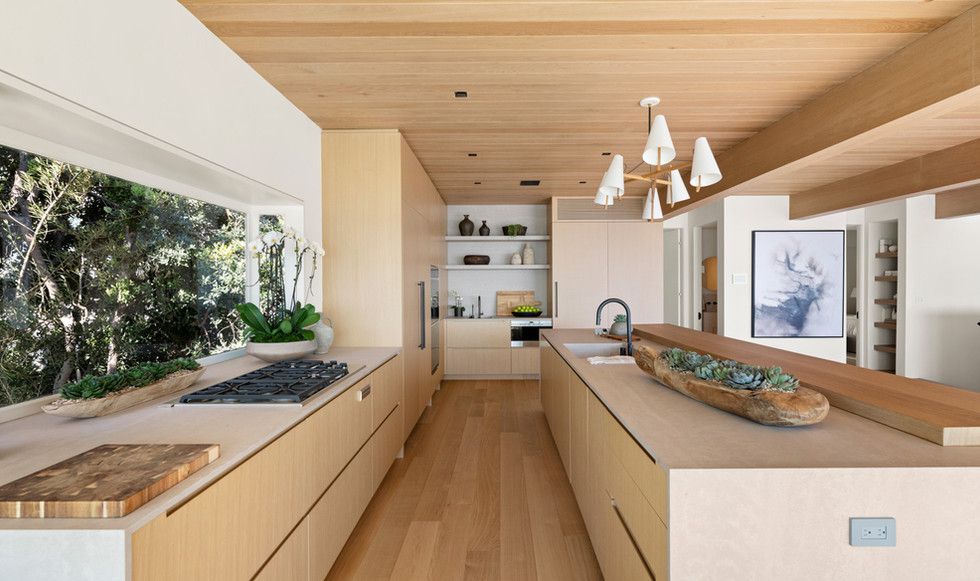 A long kitchen with wooden cabinets and a large window.