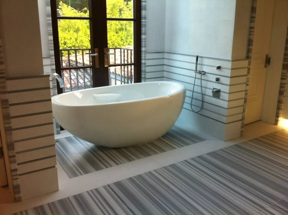 A bathtub in a bathroom with a striped floor