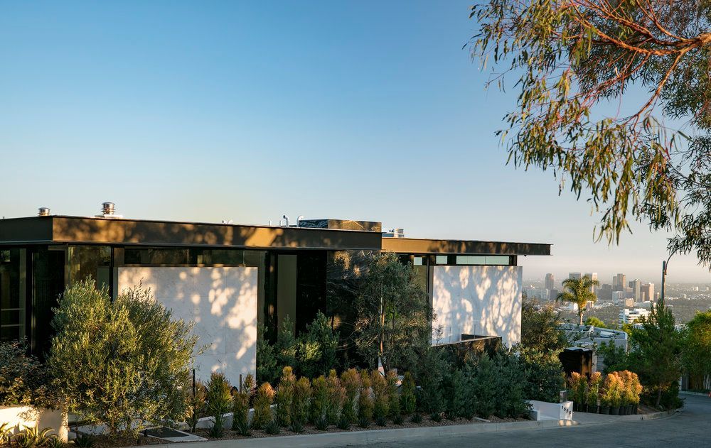 A modern house is sitting on top of a hill with a view of the city.
