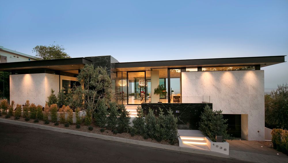 A modern house with a lot of windows is sitting on top of a hill.