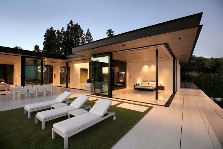 A house with a lot of windows and lounge chairs in front of it