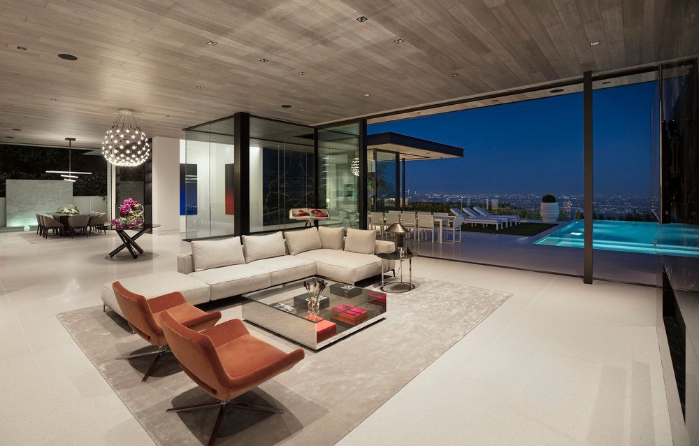 A living room with a couch , chairs , and a table with a view of a pool.