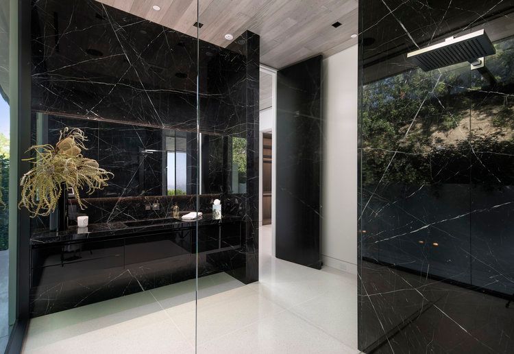 A bathroom with black marble walls and a walk in shower.