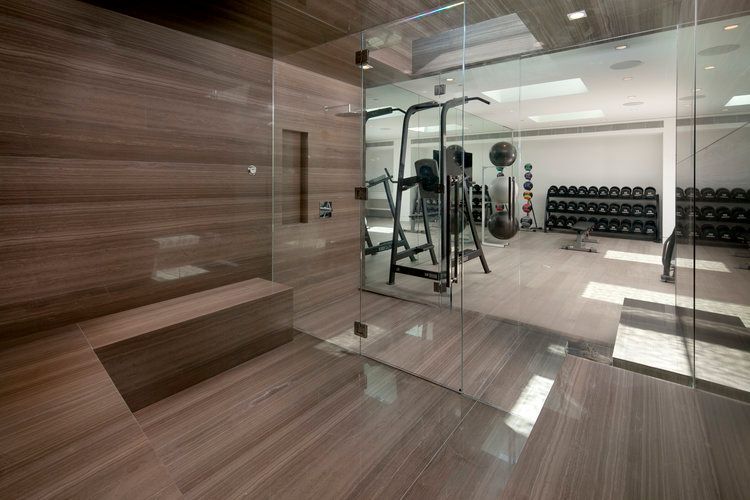 A gym with a walk in shower and a glass door.