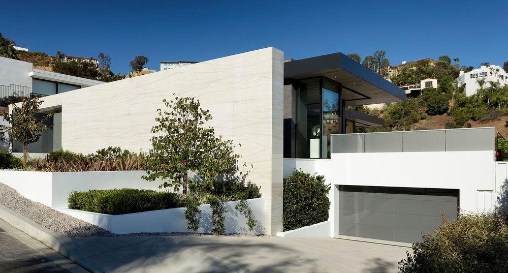 A modern house with a gray garage door is sitting on top of a hill.