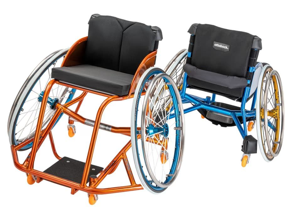 Two sports wheelchairs, orange and blue frames, large wheels, black seat and back.