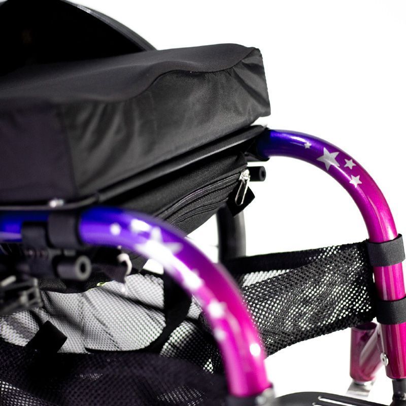 Close-up of a wheelchair with a purple and pink frame, a black seat, and a mesh storage area.