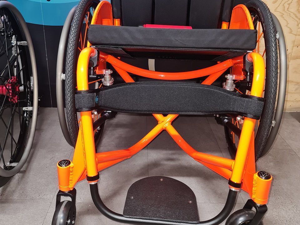 Orange and black wheelchair from a front view.