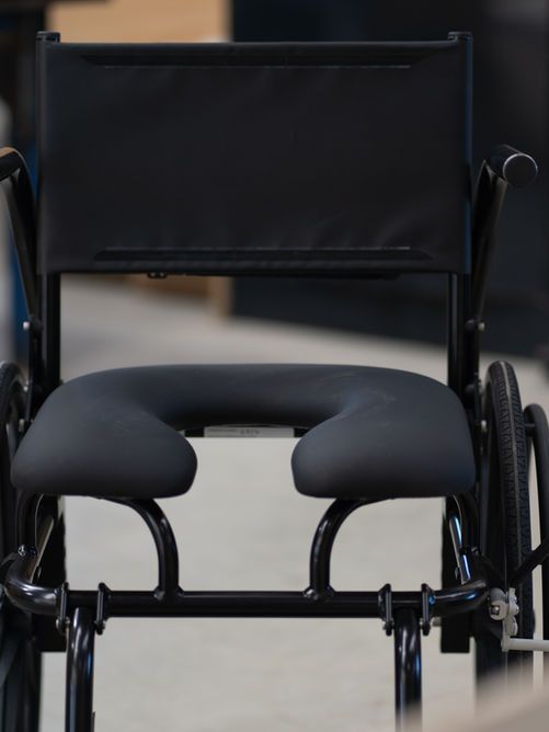 Black wheelchair with a U-shaped seat, designed for comfort and accessibility.