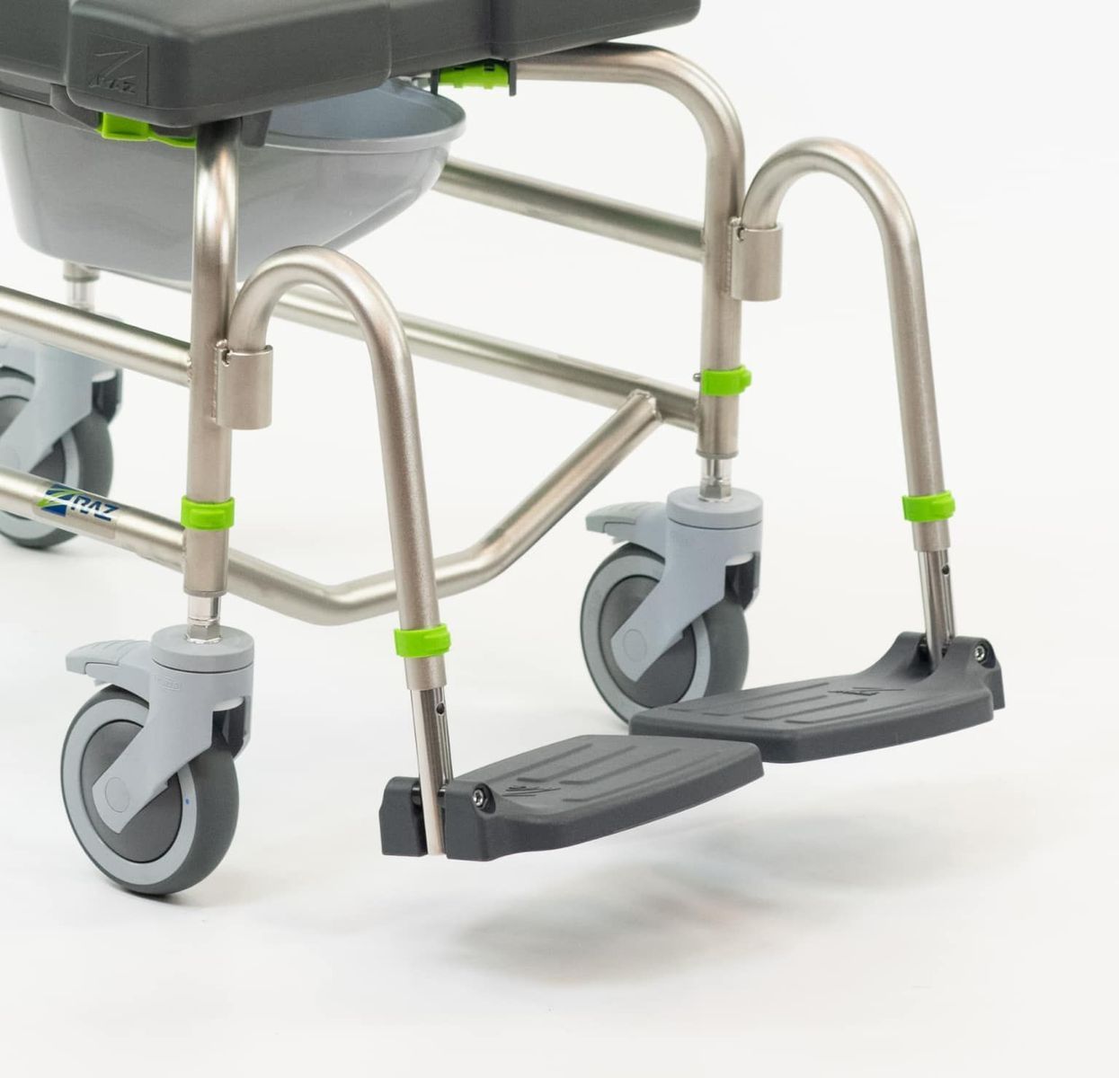 Close-up of a stainless steel commode chair with footrests and gray wheels on a white surface.