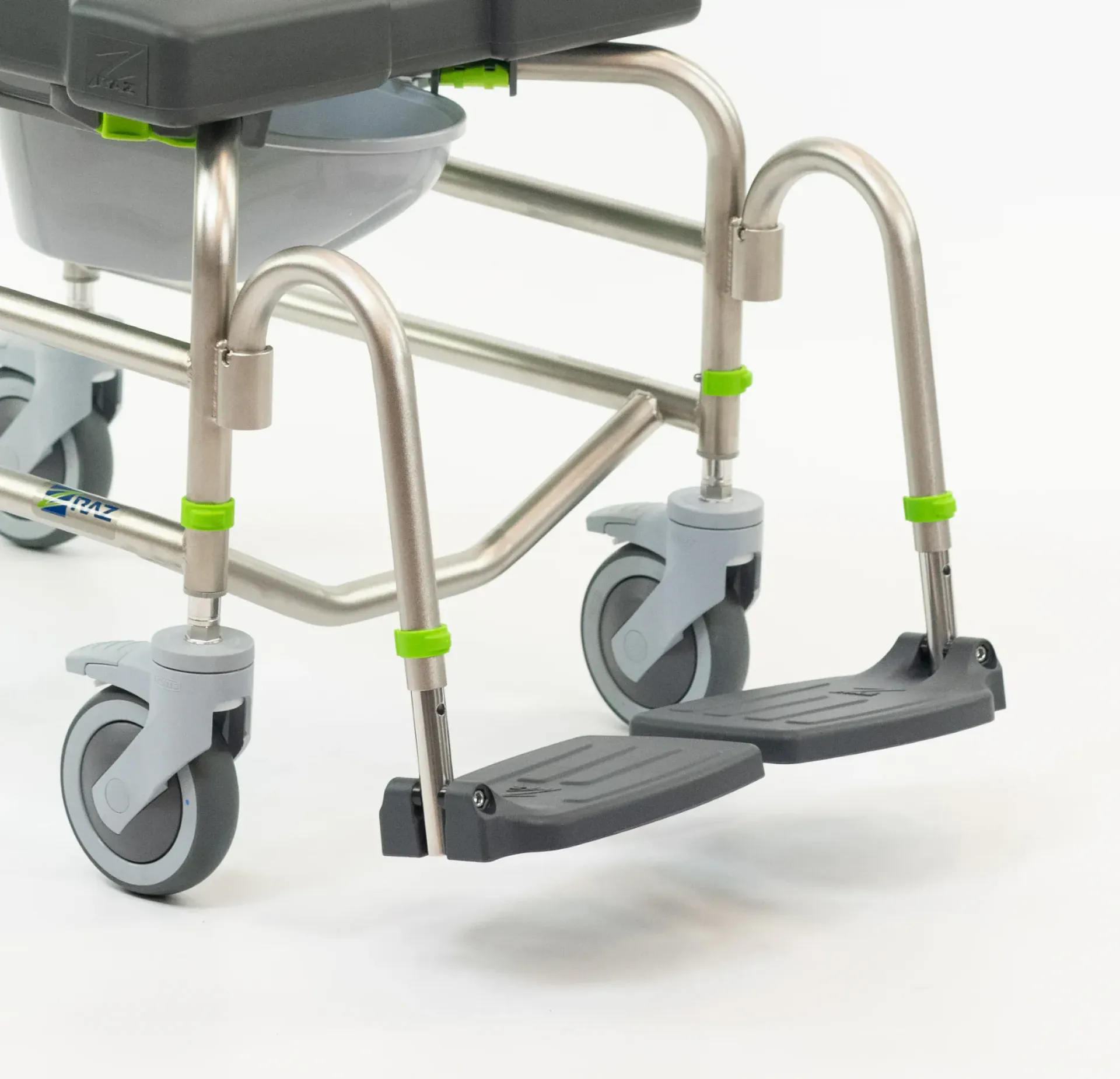 Medical commode chair with footrests and wheels. Gray and silver frame with green accents.