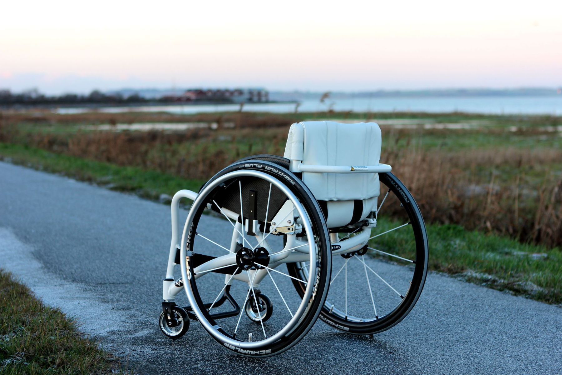 White Wolturnus Wheelchair On Path In Front Of Grass Field