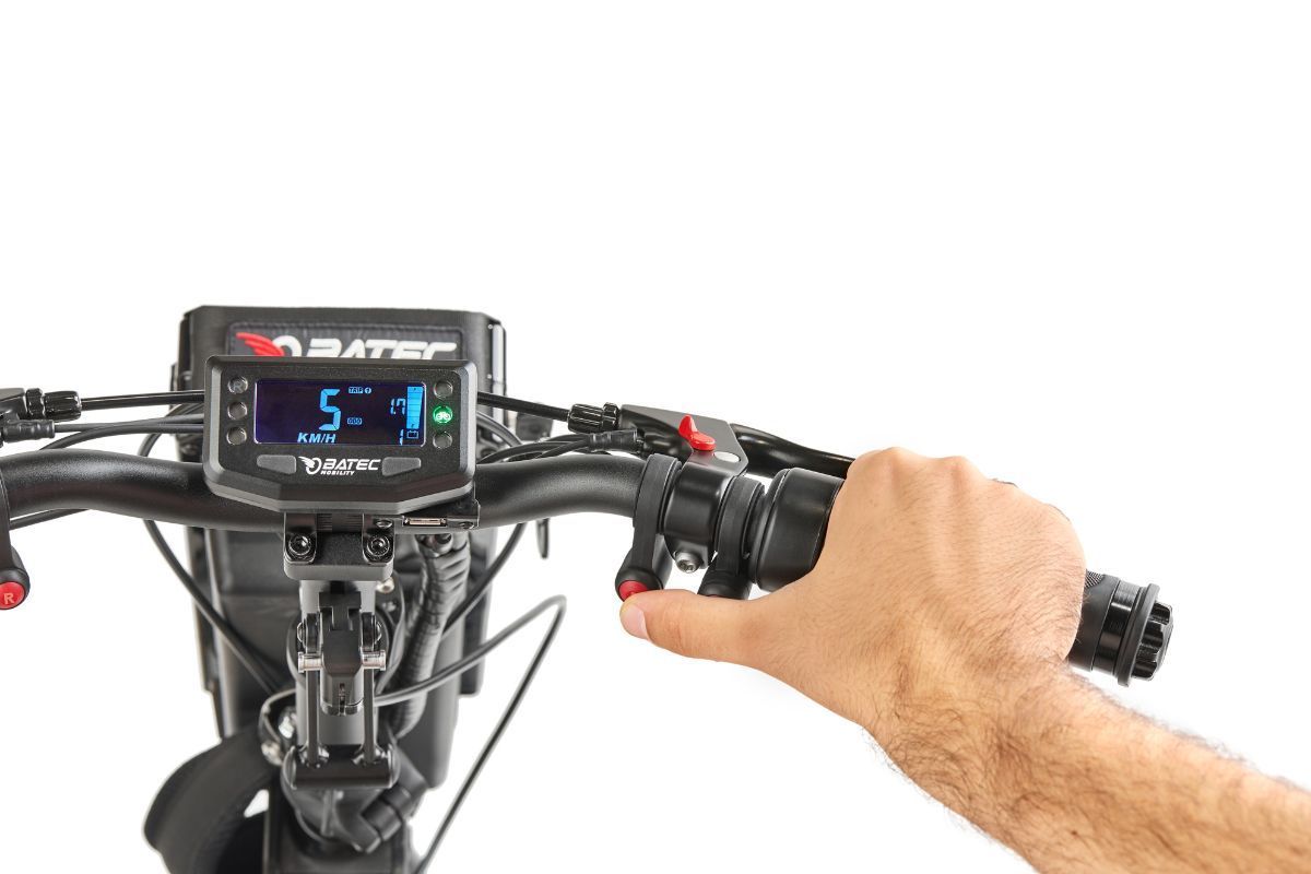 Person's hand on scooter throttle, digital display shows speed and indicators. Black handlebars.