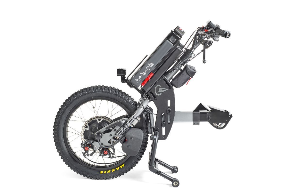 Electric wheelchair, black frame, large rear tire with red disc brakes, battery pack, controls.