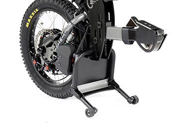 Motorcycle rear wheel mounted in a black bike stand with wheels, angled to the right.