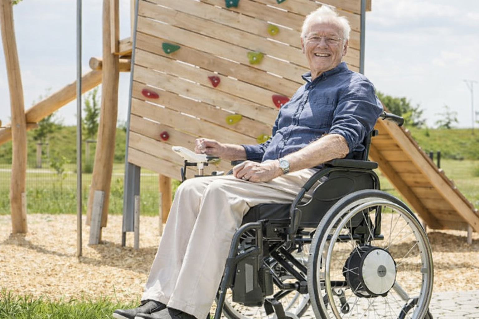 Blue and black wheelchair with large front wheels for navigating rough terrain.