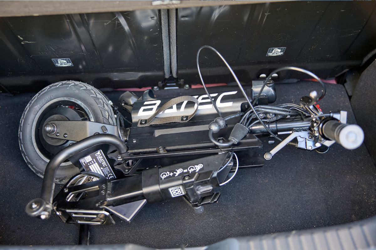Folded black electric scooter in the trunk of a car.