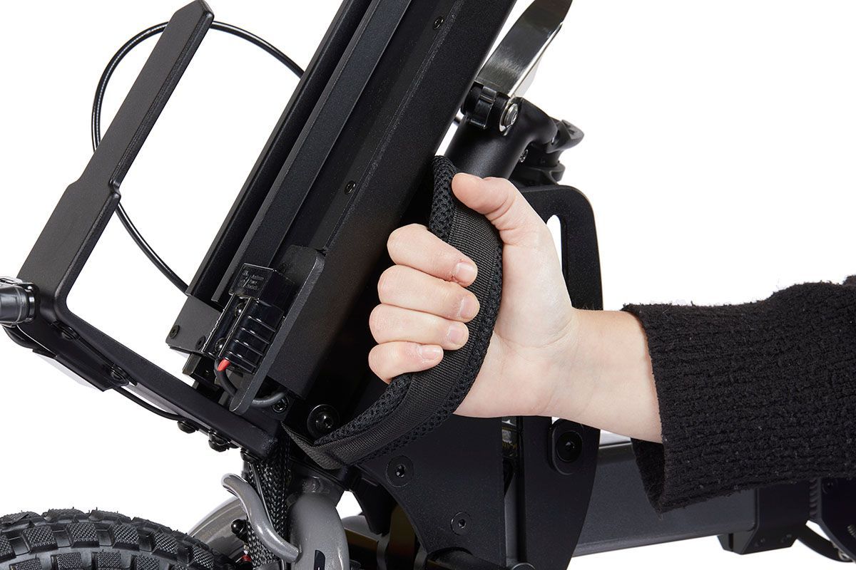 Hand gripping a black handle on a wheelchair.