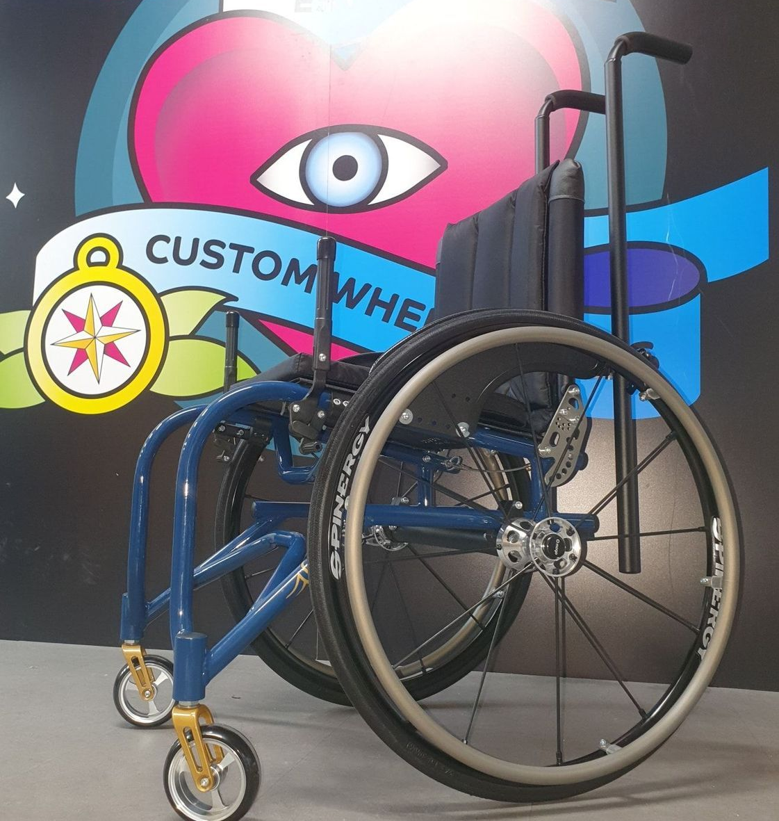 Blue wheelchair with gold accents in front of a colorful 