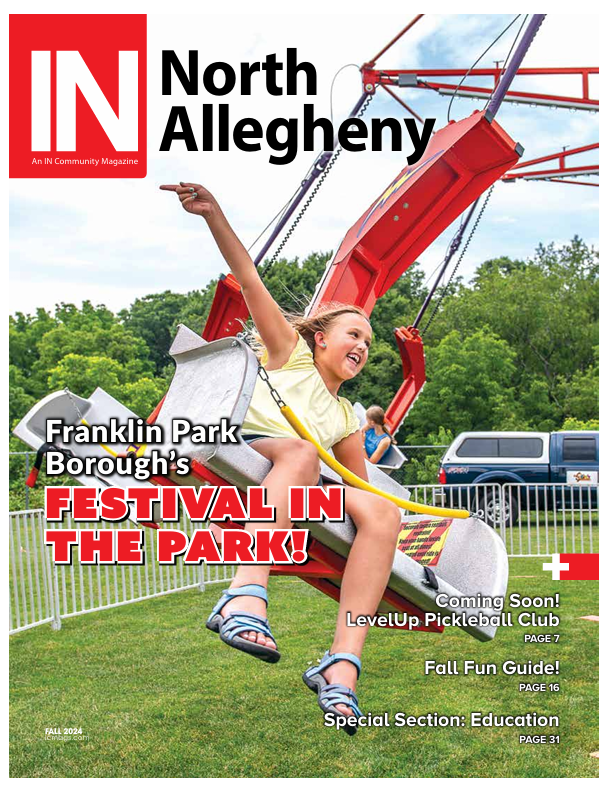 A little girl is riding a ferris wheel on the cover of a north allegheny magazine.