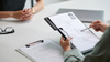 Person reviewing a resume during an interview, pointing at the document.