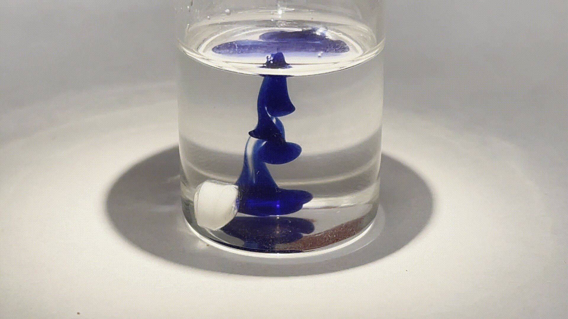 A glass of water with a blue swirl in it.
