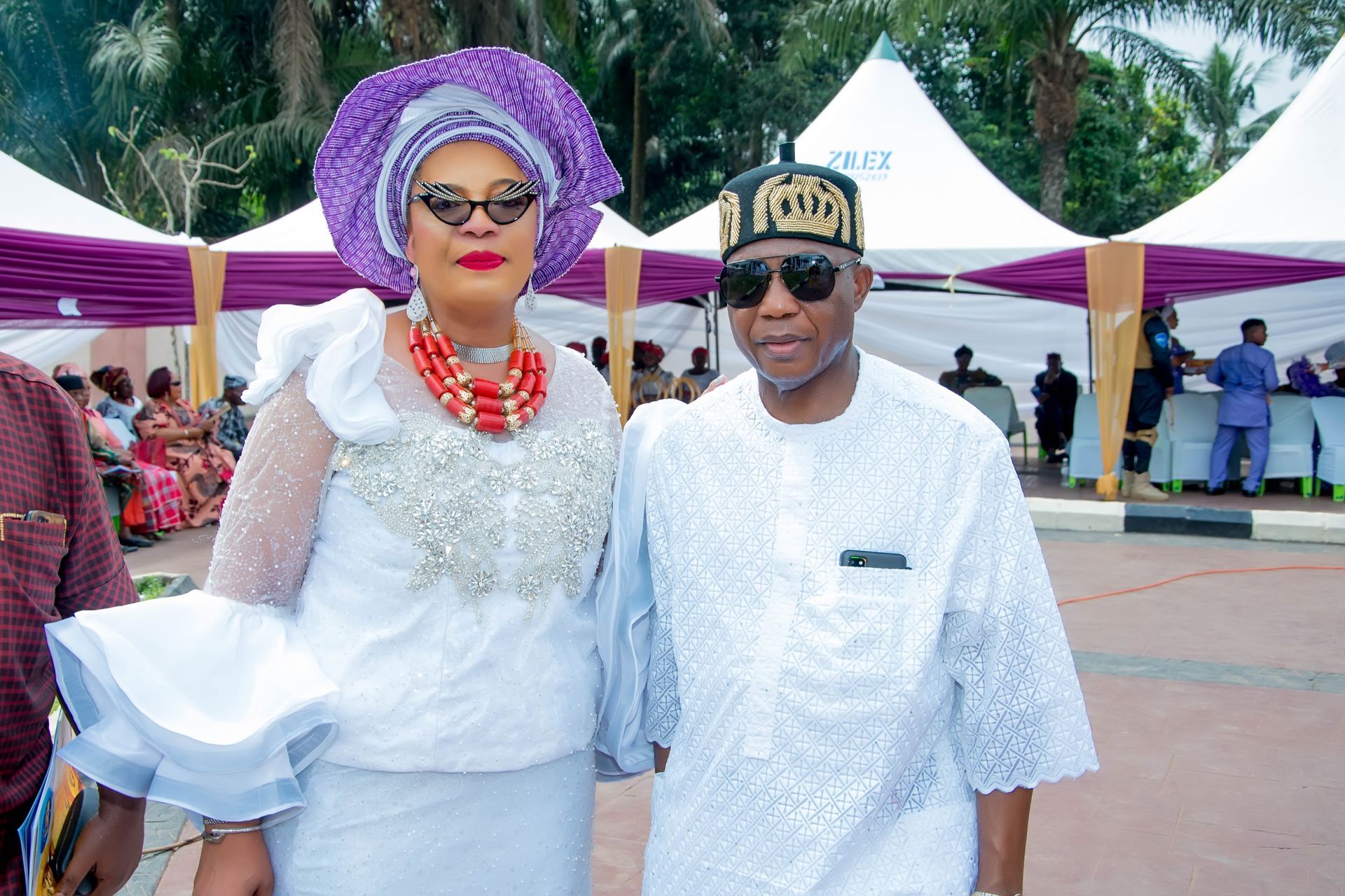 A man and a woman are posing for a picture in front of purple tents.