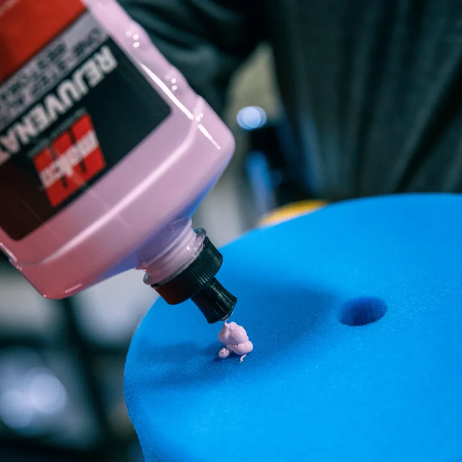 Car detailing supplies arranged on a wooden table, including polishers, bottles, and sprayers.