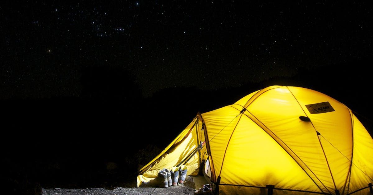 A yellow tent is lit up at night under a starry sky.