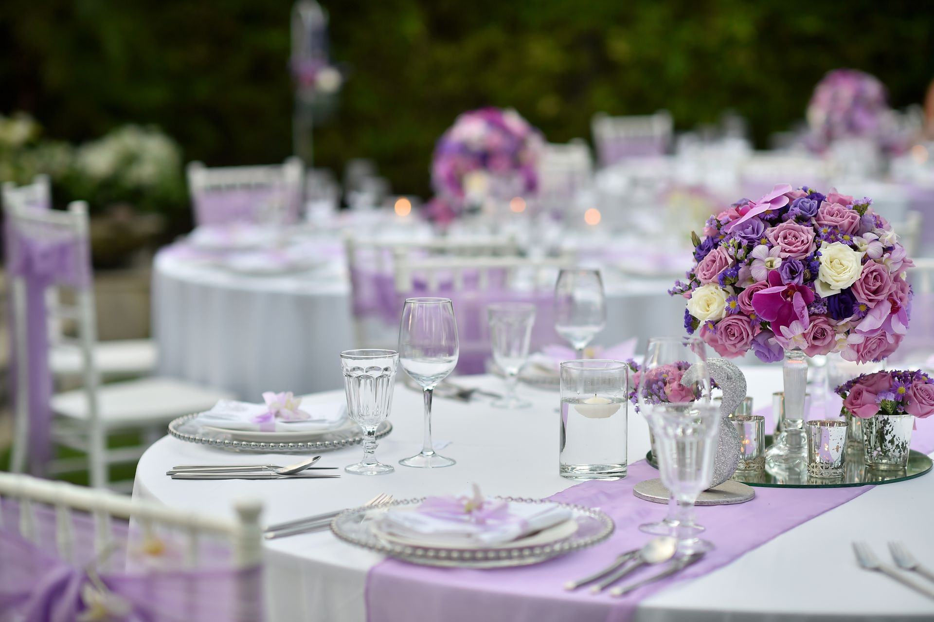 A table set for a wedding reception with purple flowers on it.