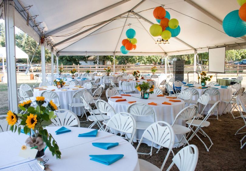 Tables and chairs under a tent with balloons hanging from the ceiling