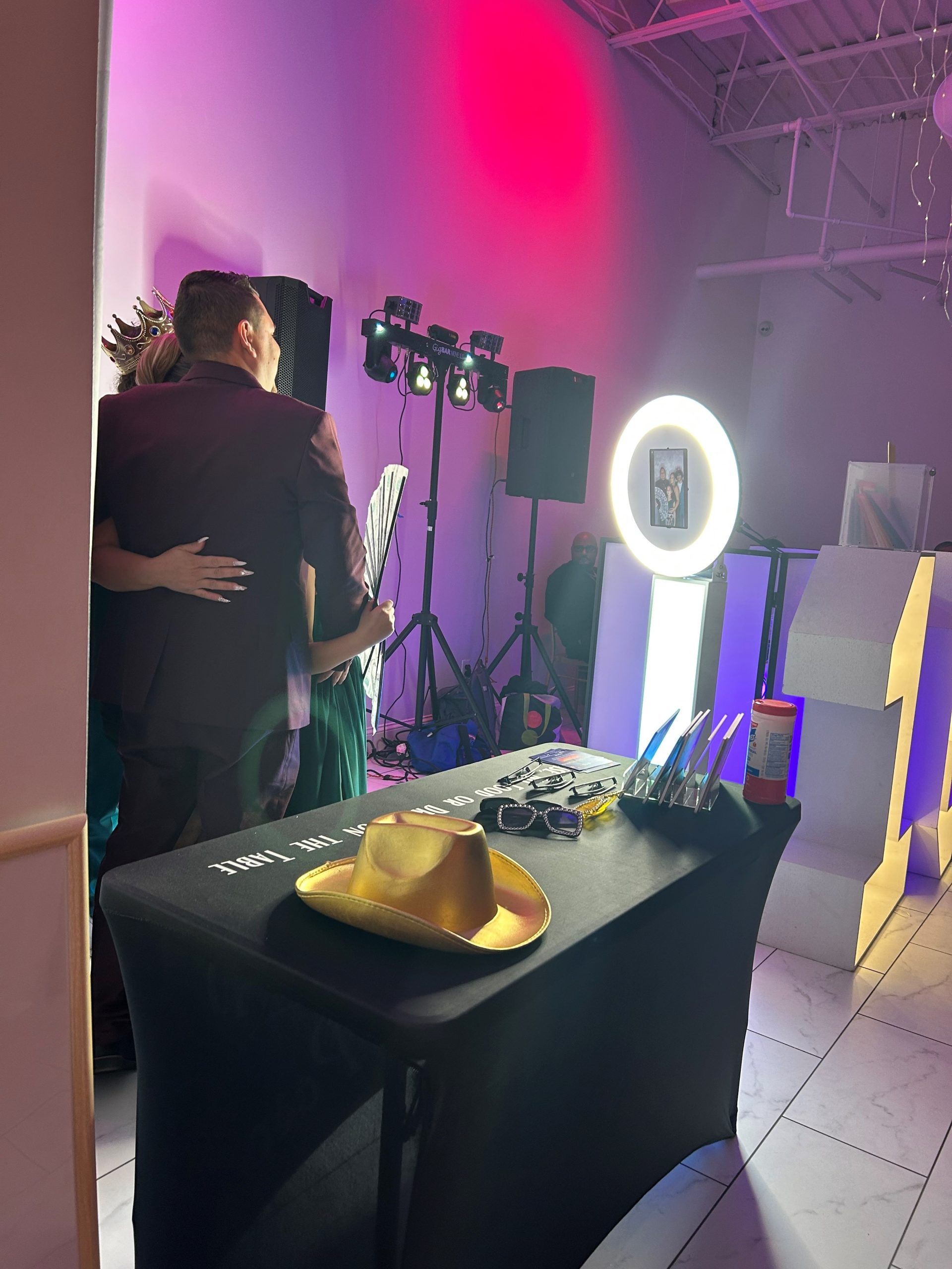 A man and woman are hugging in a room with a table and a cowboy hat on it.