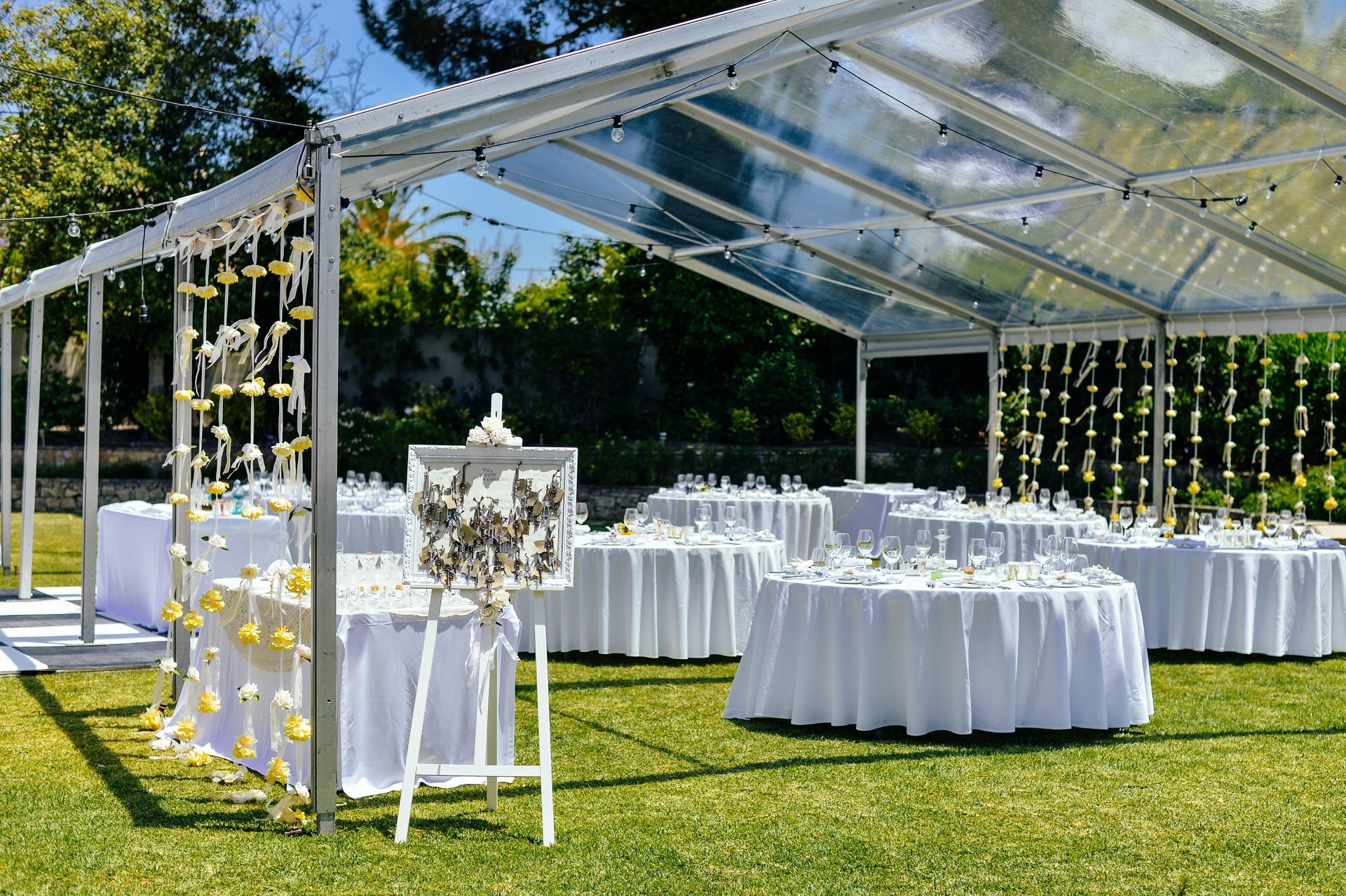 A clear tent with tables and chairs underneath it in a field.