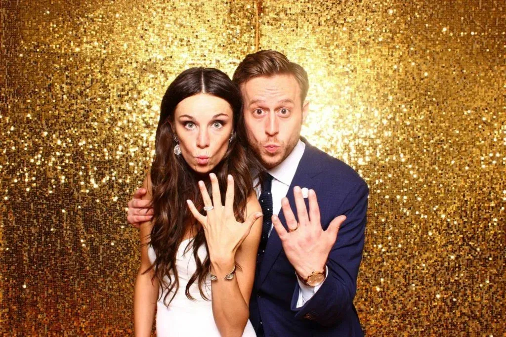 A bride and groom are posing for a picture in a photo booth.