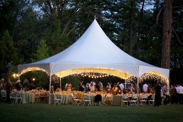 A large white tent with tables and chairs underneath it.