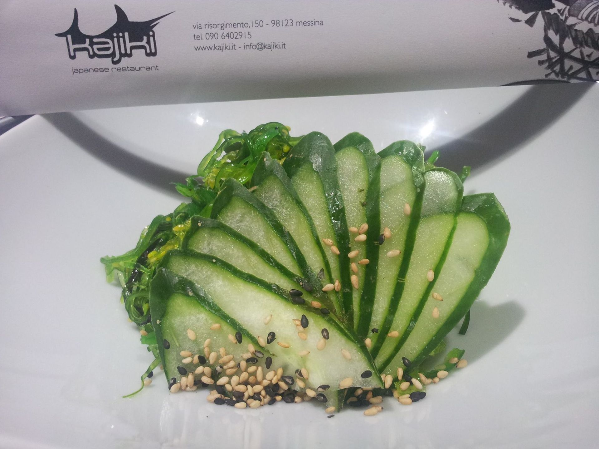 Un piatto bianco guarnito con cetrioli a fette e semi di sesamo