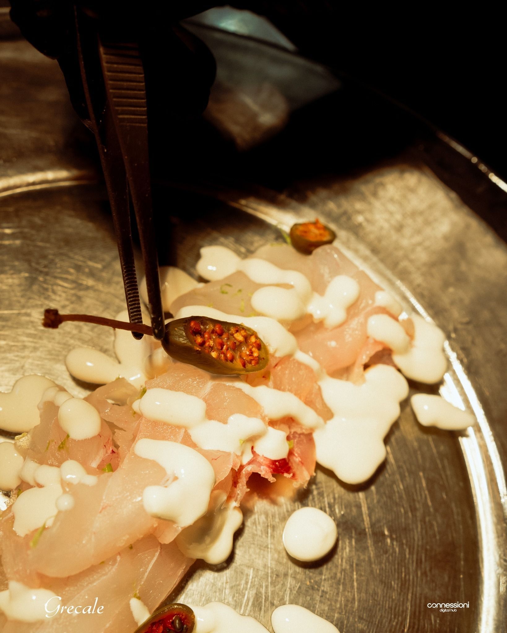 Una persona tiene in mano un cetriolo sottaceto sopra un piatto di cibo.