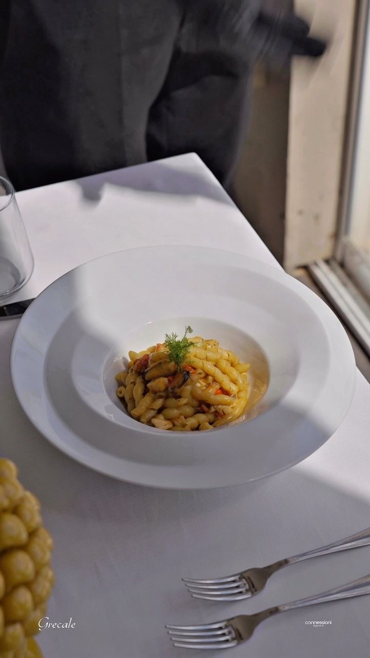 Un piatto bianco con sopra della pasta e una forchetta su un tavolo.