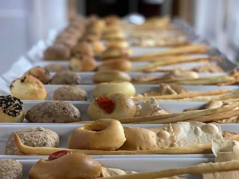 A row of trays filled with different types of bread and pastries.