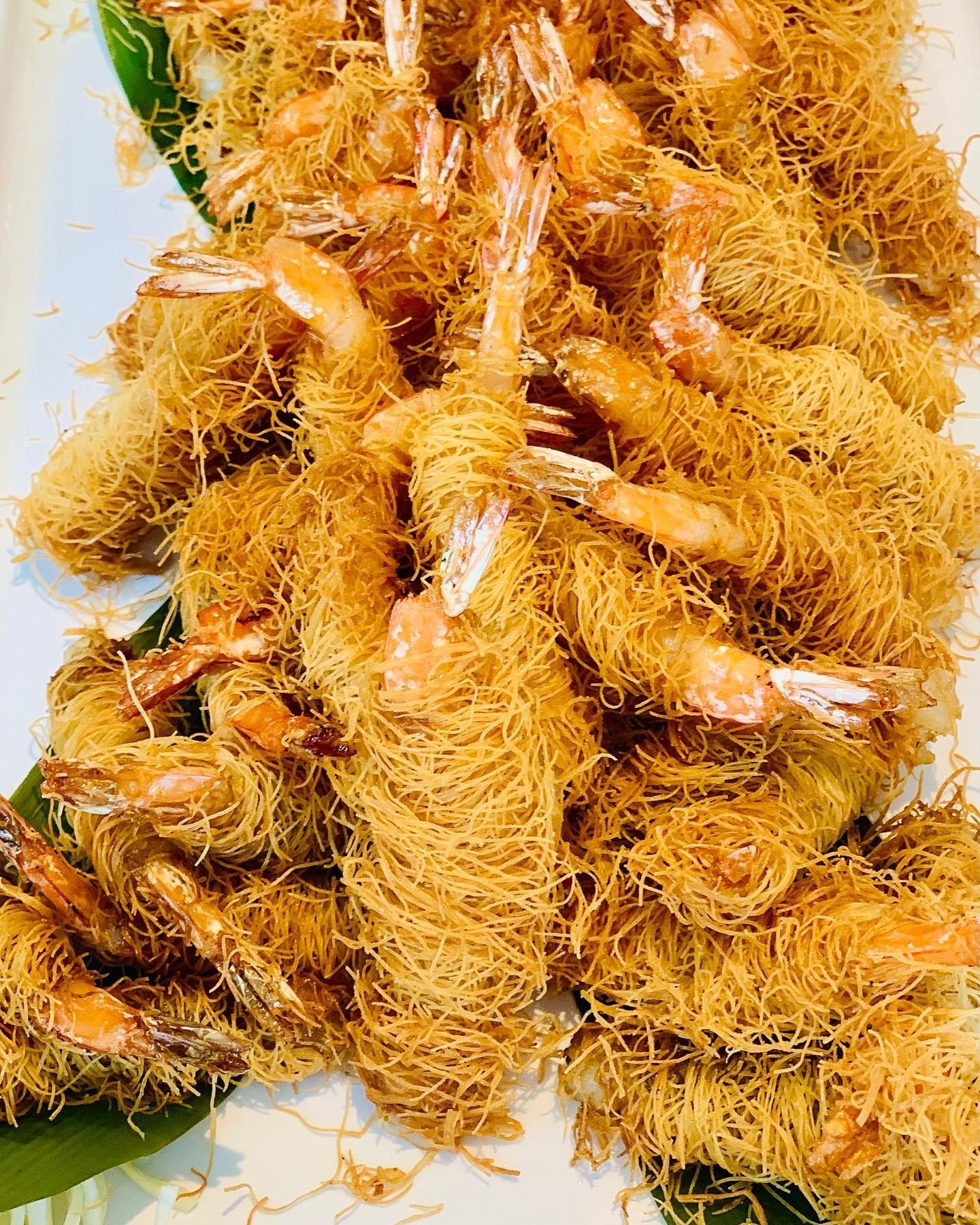 Un primo piano di gamberi fritti su un piatto bianco.