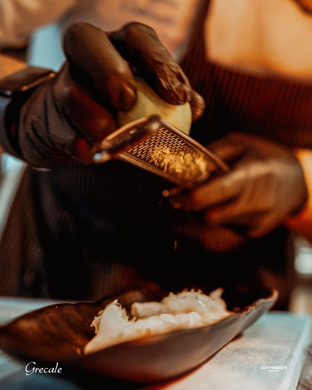 Una persona che indossa guanti neri che grattugia una cipolla in una ciotola